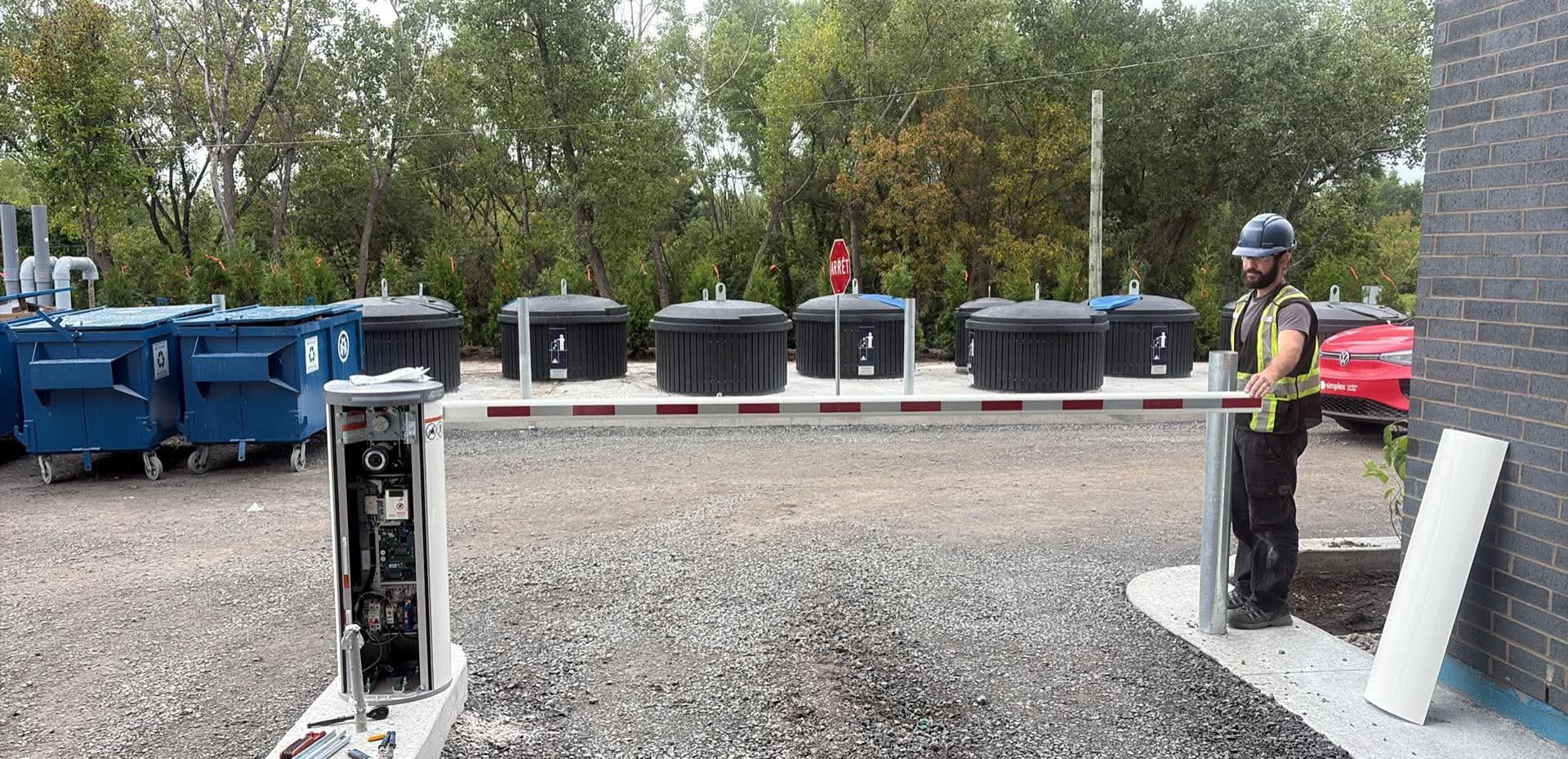 Technician beside an automatic barrier with an open cabinet and a horizontal arm