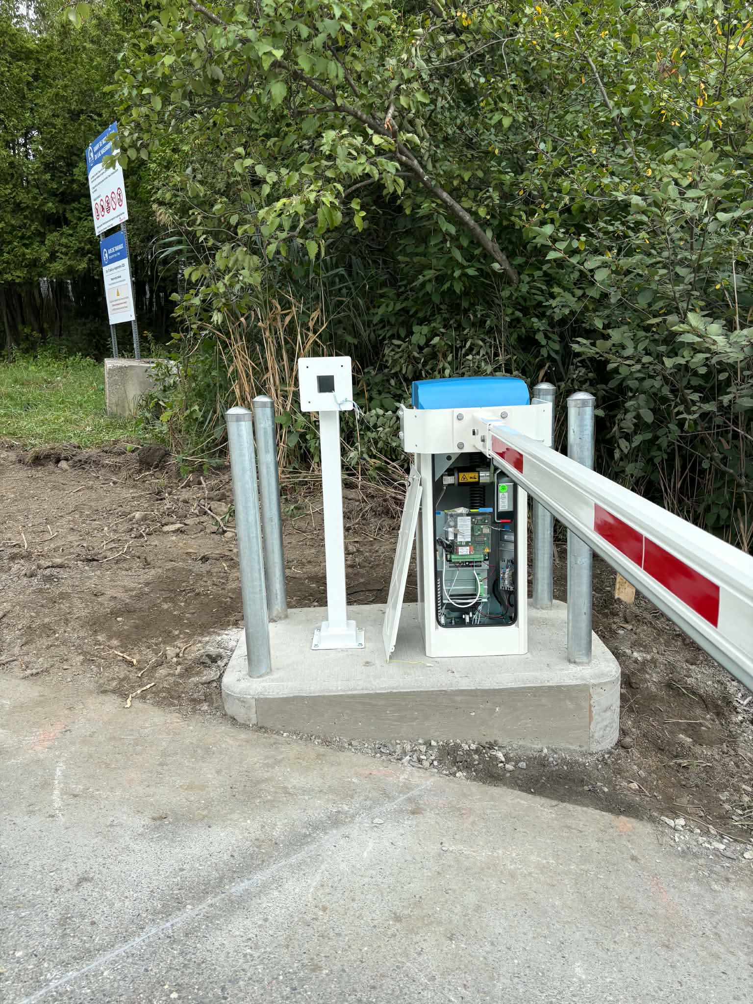 Barrier, access reader and protective bollards on a compact concrete island at a boat ramp